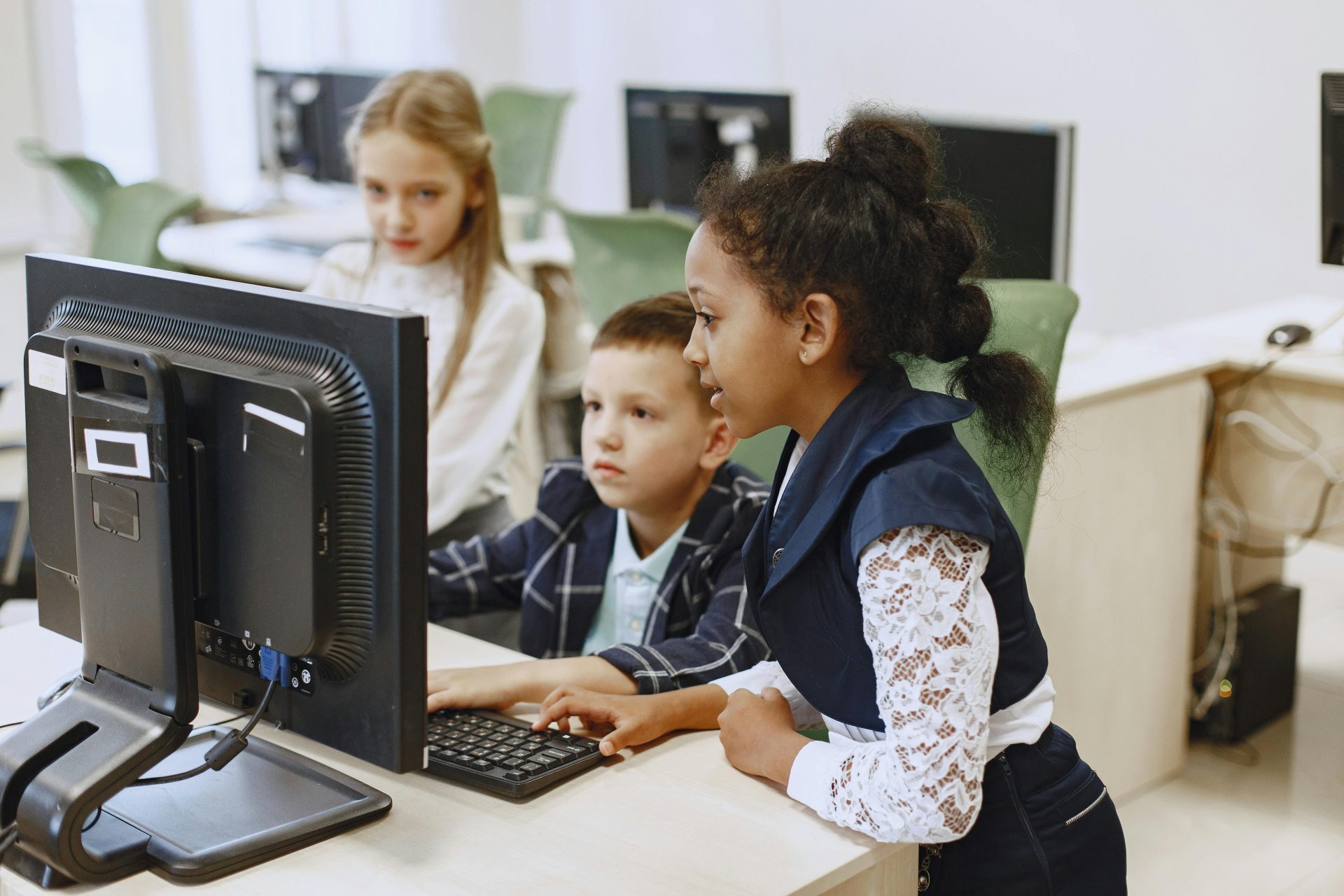 Eine vielfältige Gruppe von Kindern arbeitet gemeinsam an Computern in einem modernen Klassenzimmer.
