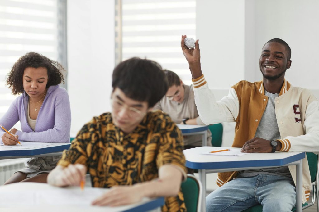 Des étudiants passant un examen dans une salle de classe diversifiée, mêlant concentration et interactions ludiques.